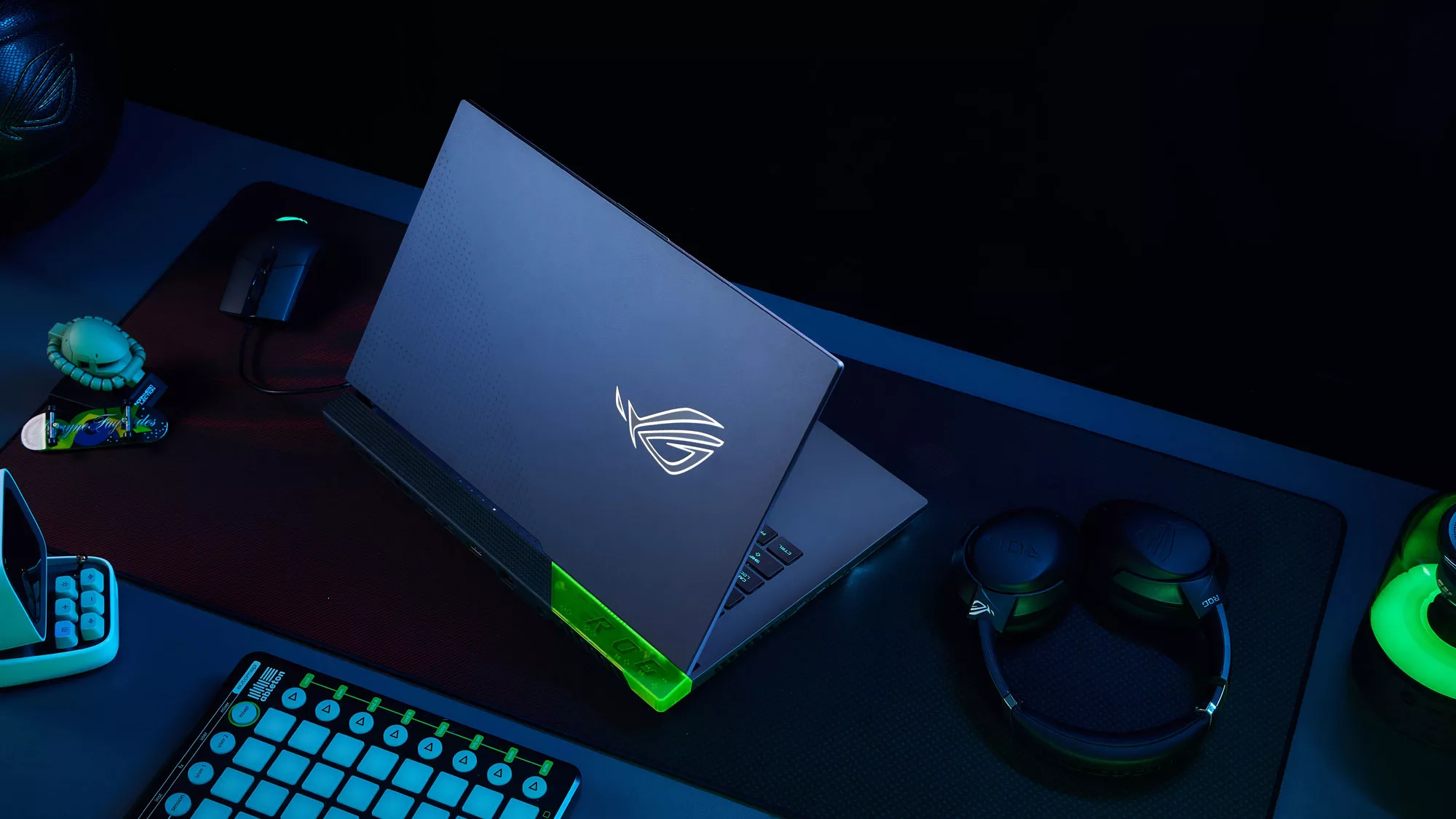 Photo of the Strix SCAR laptop, with a wired mouse and wireless headset on a large deskpad.