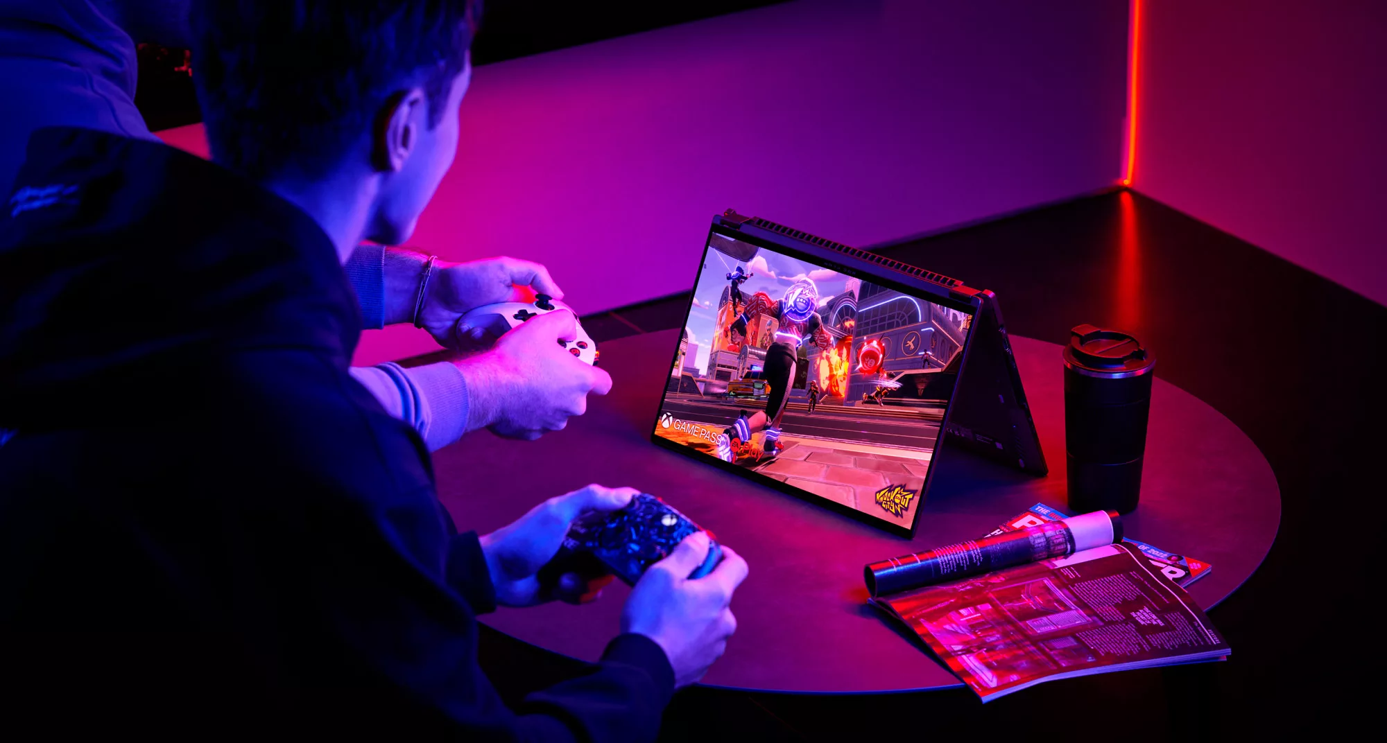 An image of two people playing video games on the ROG Flow X16 in tent mode, using game controllers.