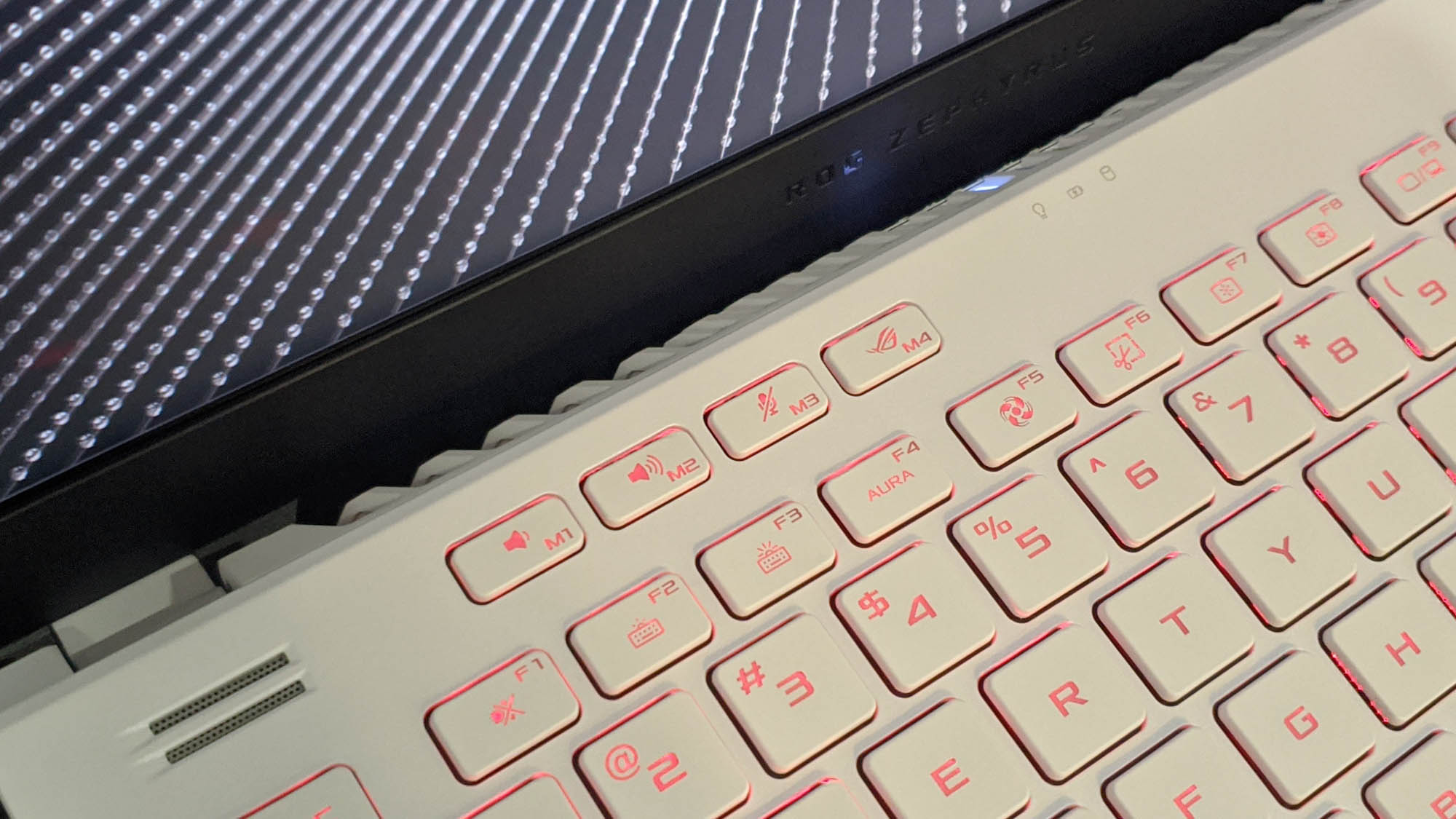 A close-up photo of the Zephyrus G14's keyboard, glowing with a red backlight.
