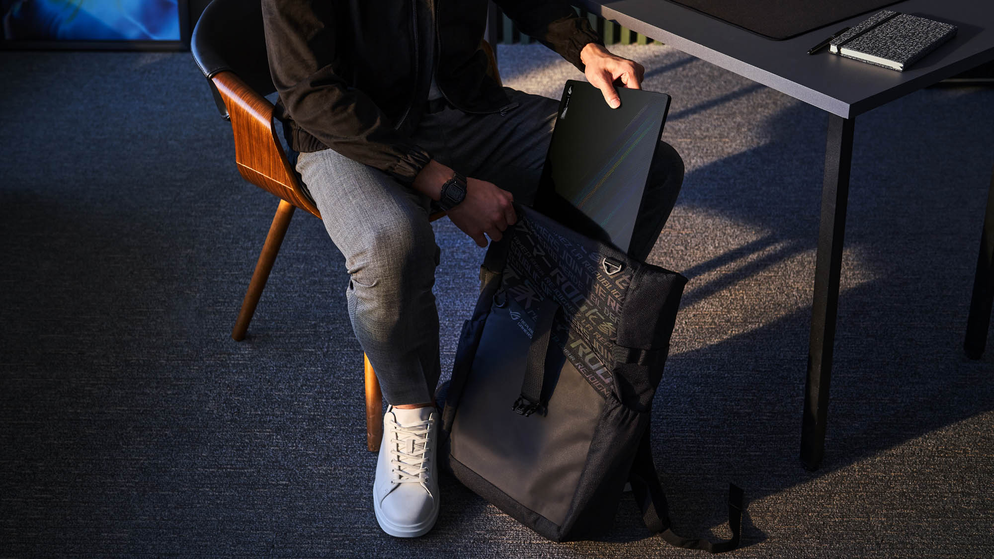 A photo of a student putting the Zephyrus M16 laptop into a backpack.