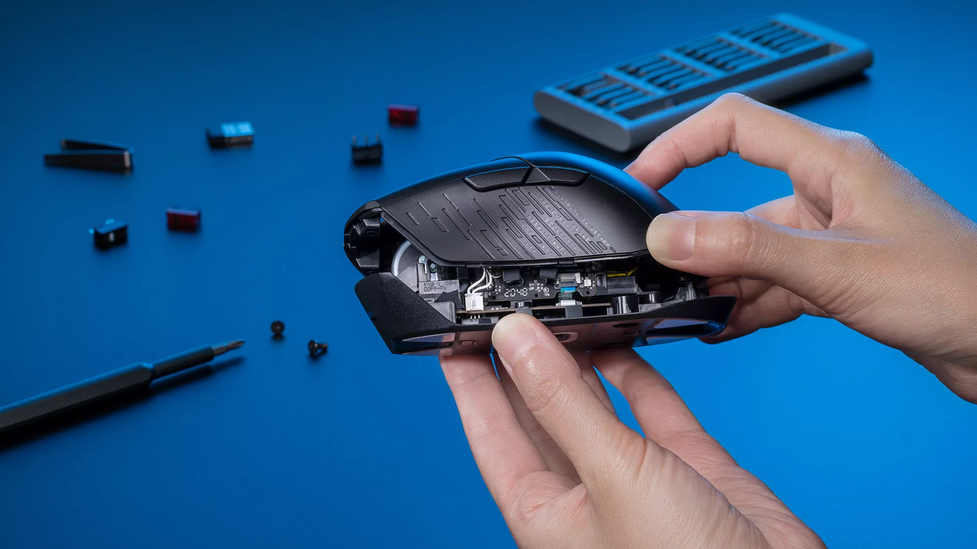 A photo of a hand removing the top cover of a gaming mouse to reveal the internals.