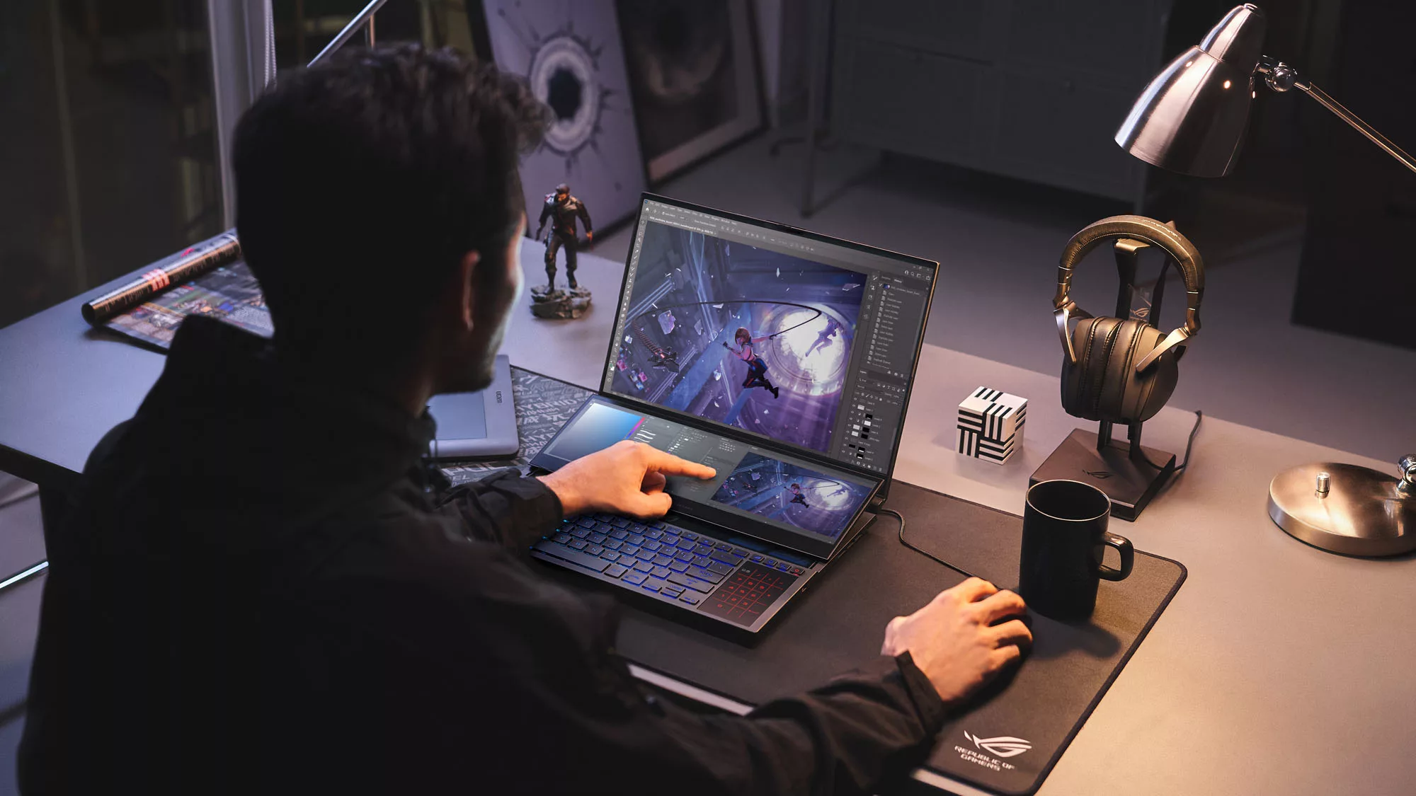 Фотография Zephyrus Duo 16 на столе, где пользователь держит мышь и касается дополнительного дисплея ScreenPad Plus.