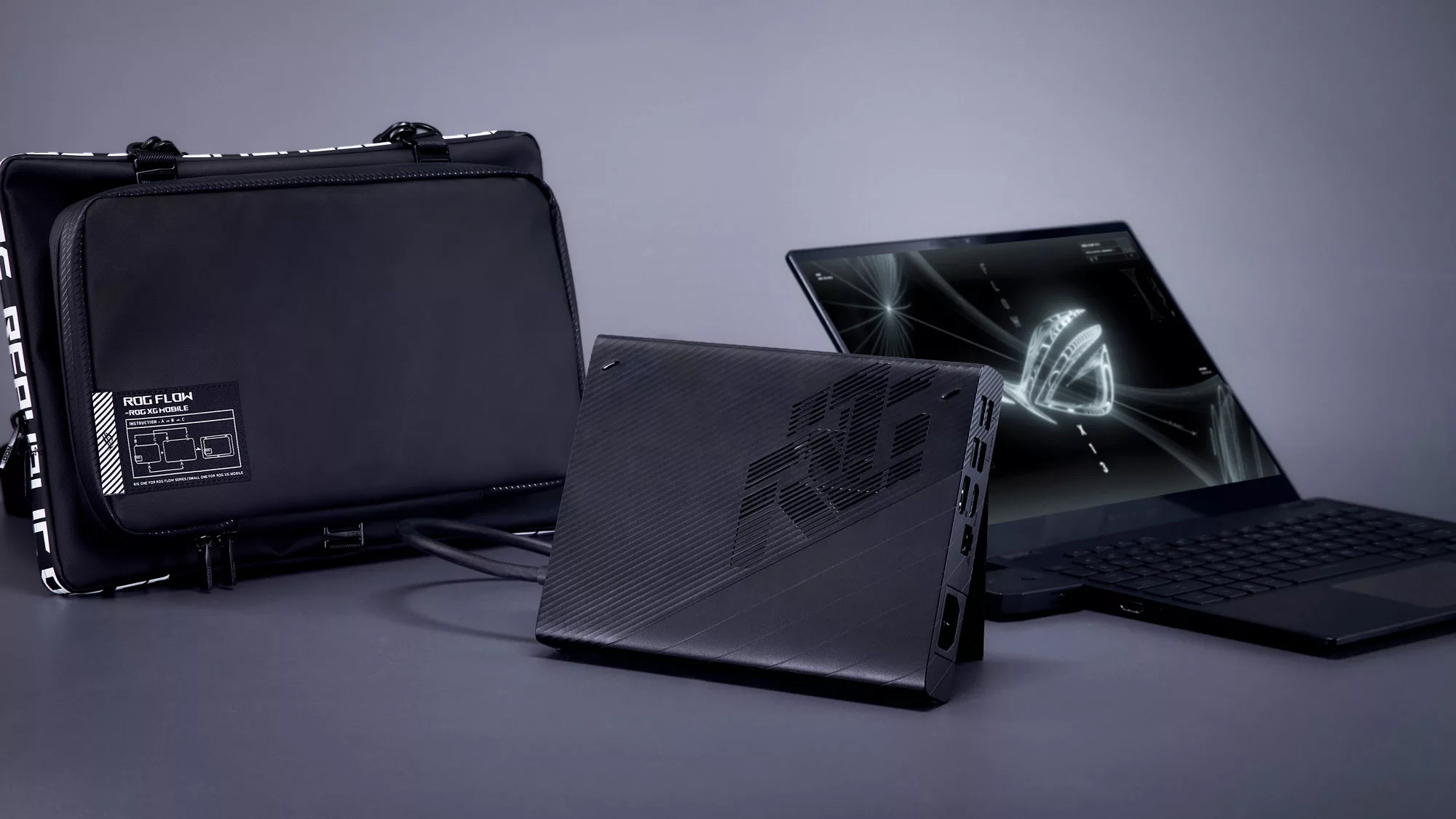 A photo of the Flow X13 laptop sitting next to an XG Mobile and Flow-branded laptop bag.