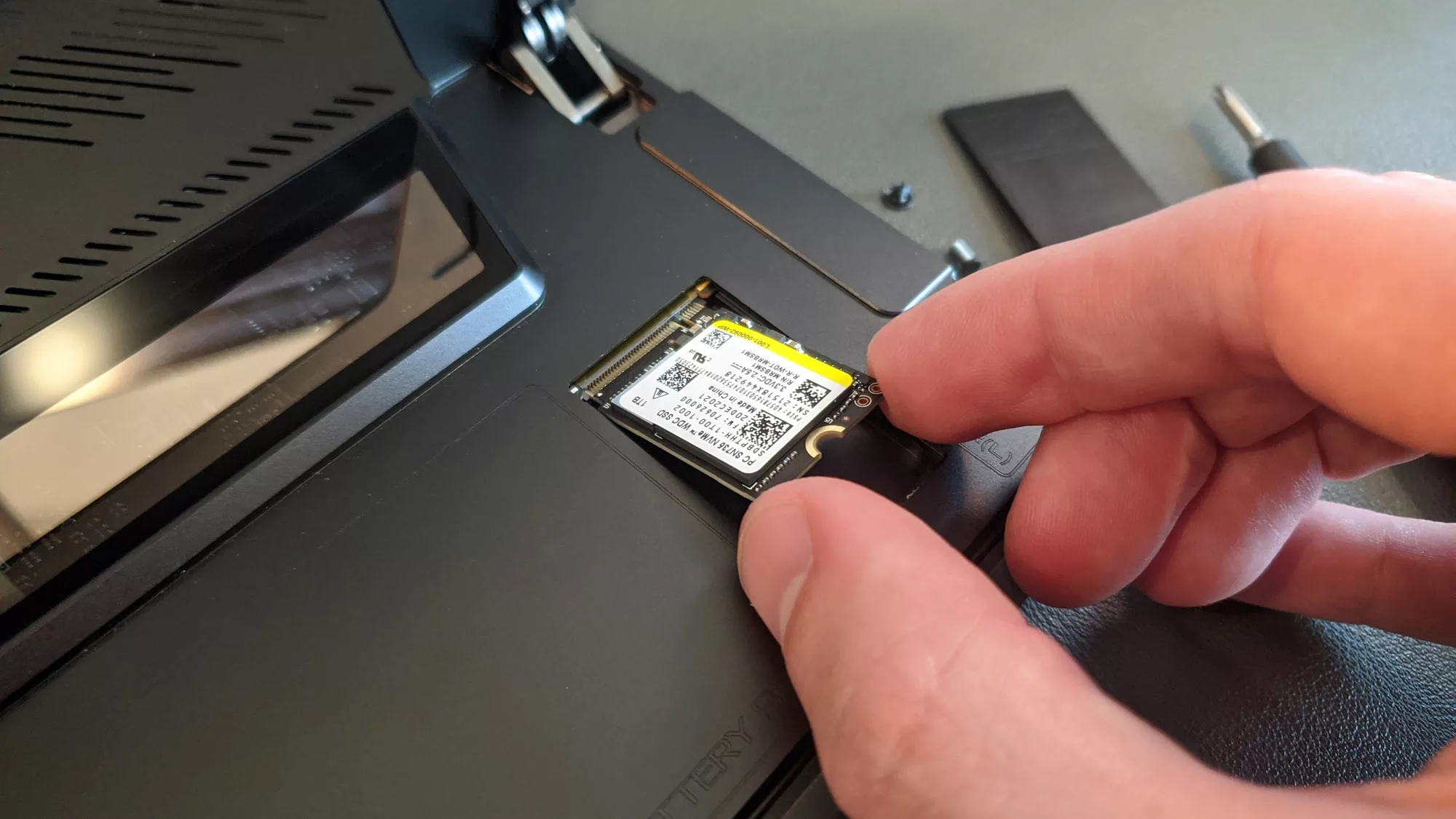 A photo of a hand removing the SSD from the Flow Z13 tablet.