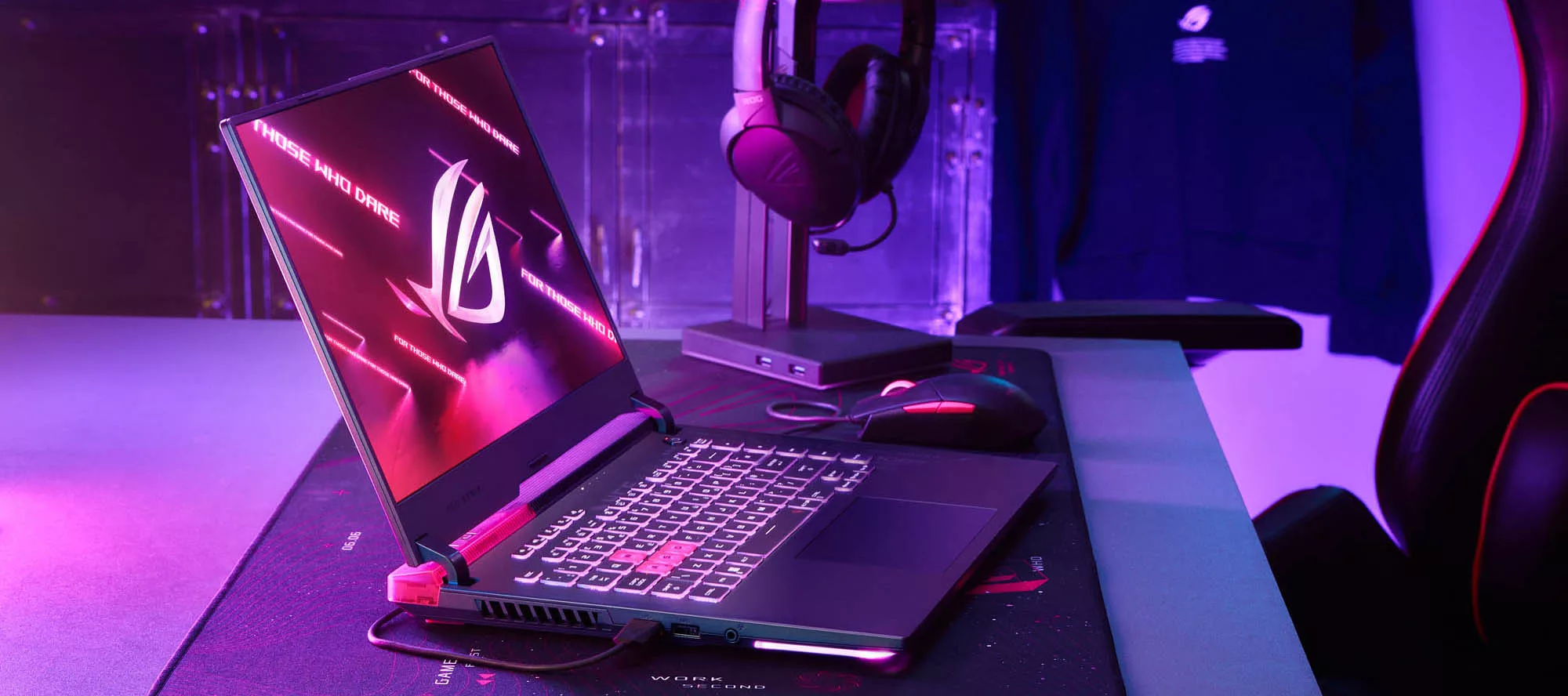 An ROG Strix G15 laptop sitting on a desk surrounded by purple lighting.