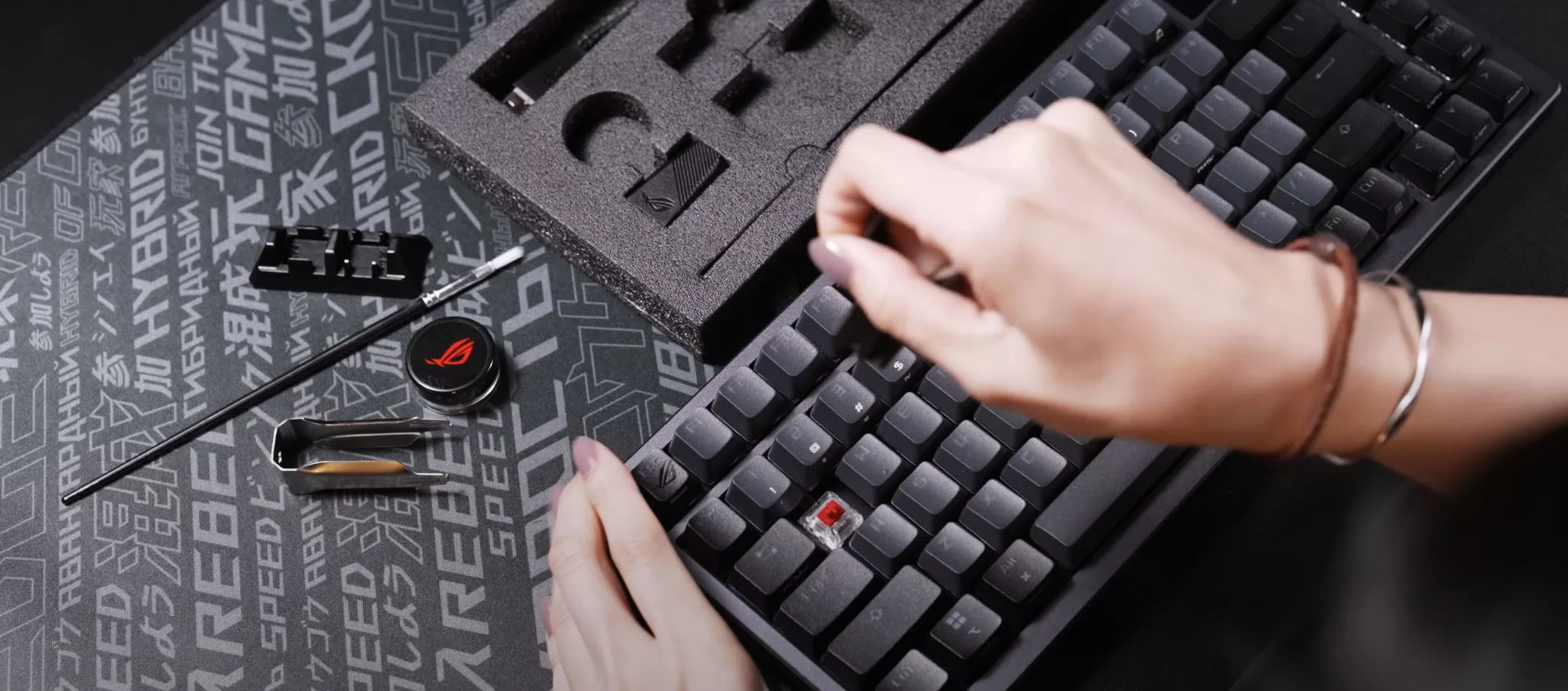 A hand removing a keycap from the ROG Azoth keyboard.