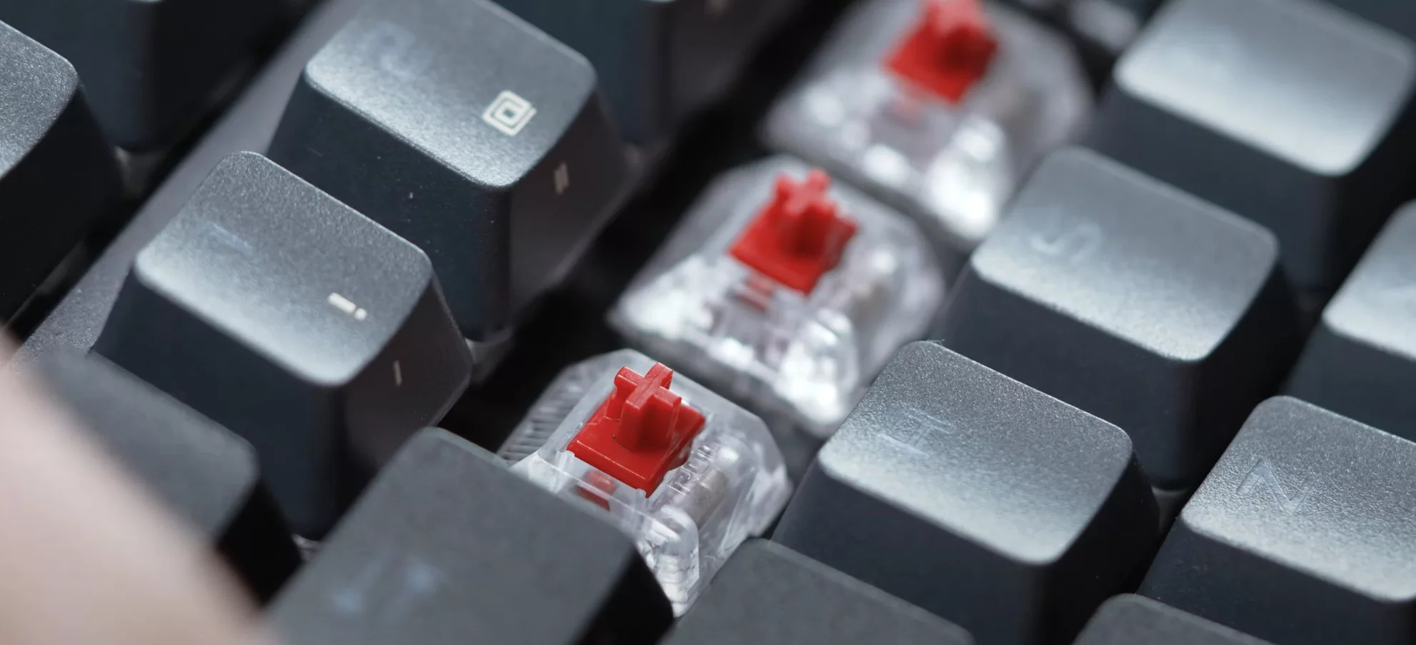 Three exposed red keyboard switches inside the ROG Azoth keyboard.