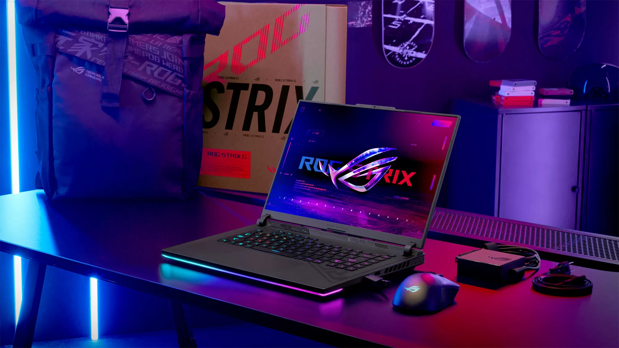 The ROG Strix G16 on a desk next to a backpack and box with the Strix label visible.