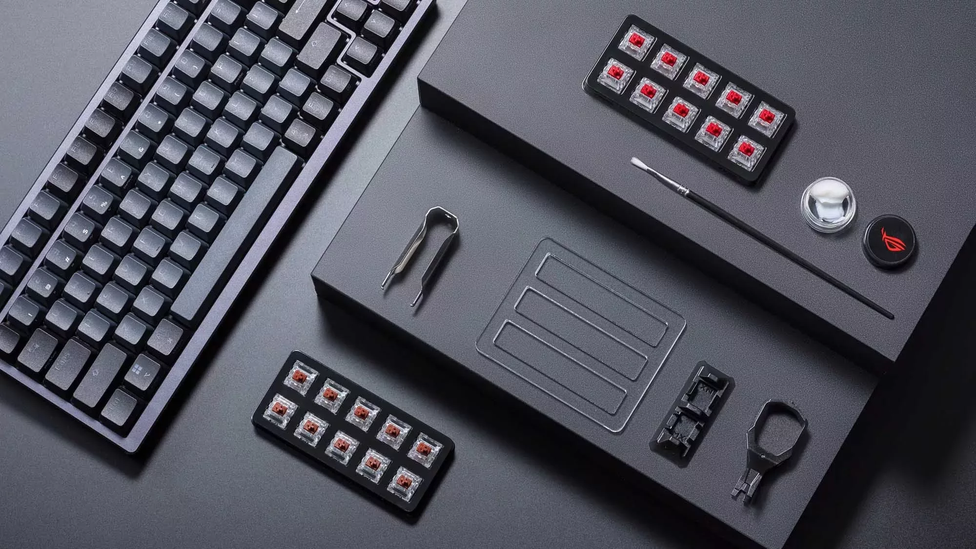 Die ROG Azoth-Tastatur auf einem Schreibtisch neben einem Kit mit Schmiermitteln.