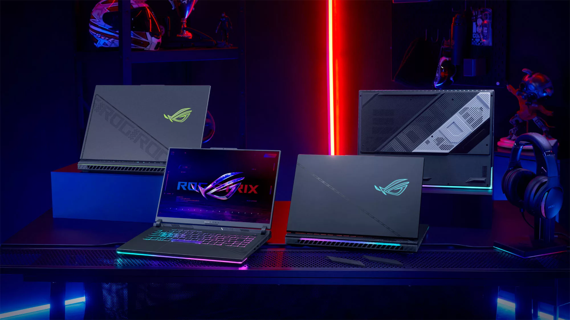 Four ROG Strix laptops facing opposite directions on a table.