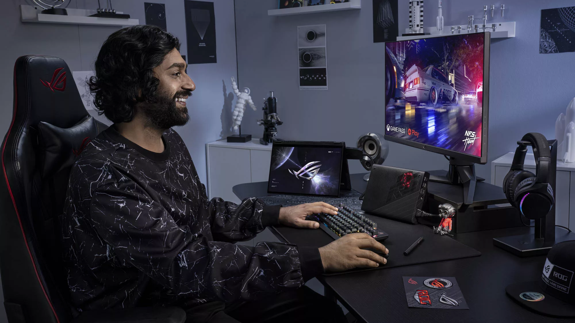Мужчина сидит за столом с Flow X13 в режиме ожидания, подключенным к XG Mobile и внешнему монитору с игрой на экране.