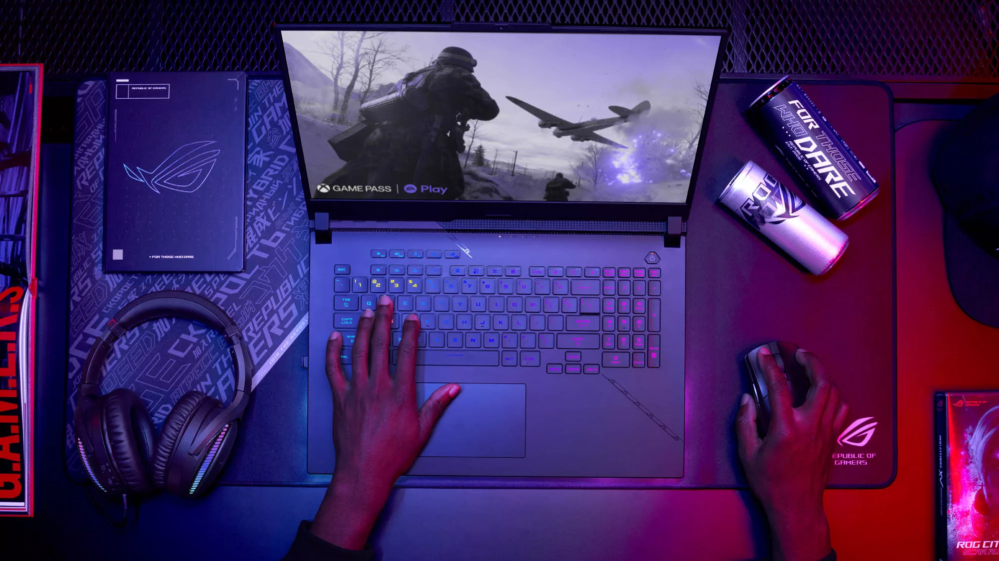 The ROG Strix SCAR 17 sitting on a desk, with two hands on the machine playing a game on-screen.