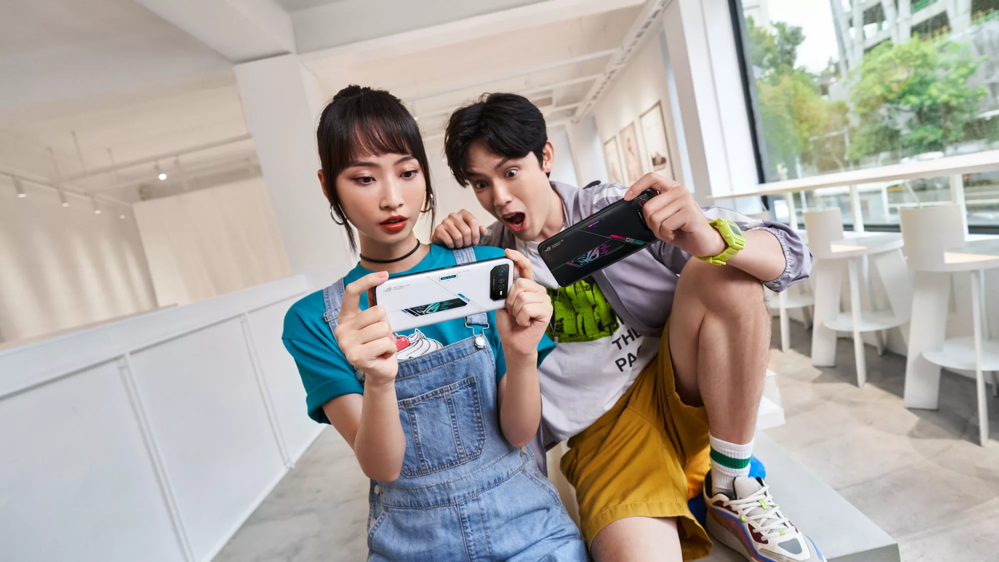 Two people holding ROG phones in landscape mode, with mouths open excitedly.