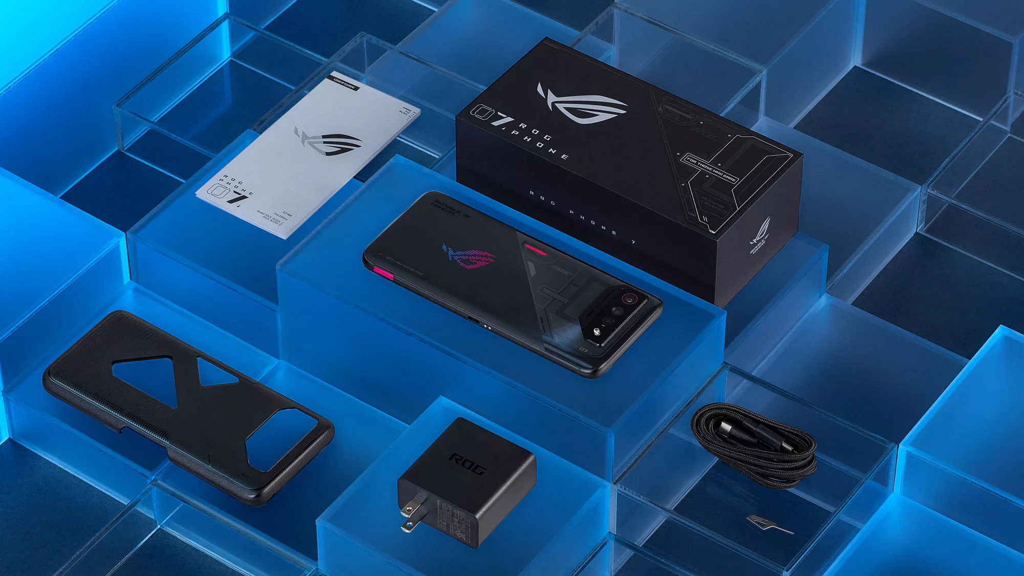 The black ROG Phone 7 face-down on a blue pedestal, surrounded by the included accessories.