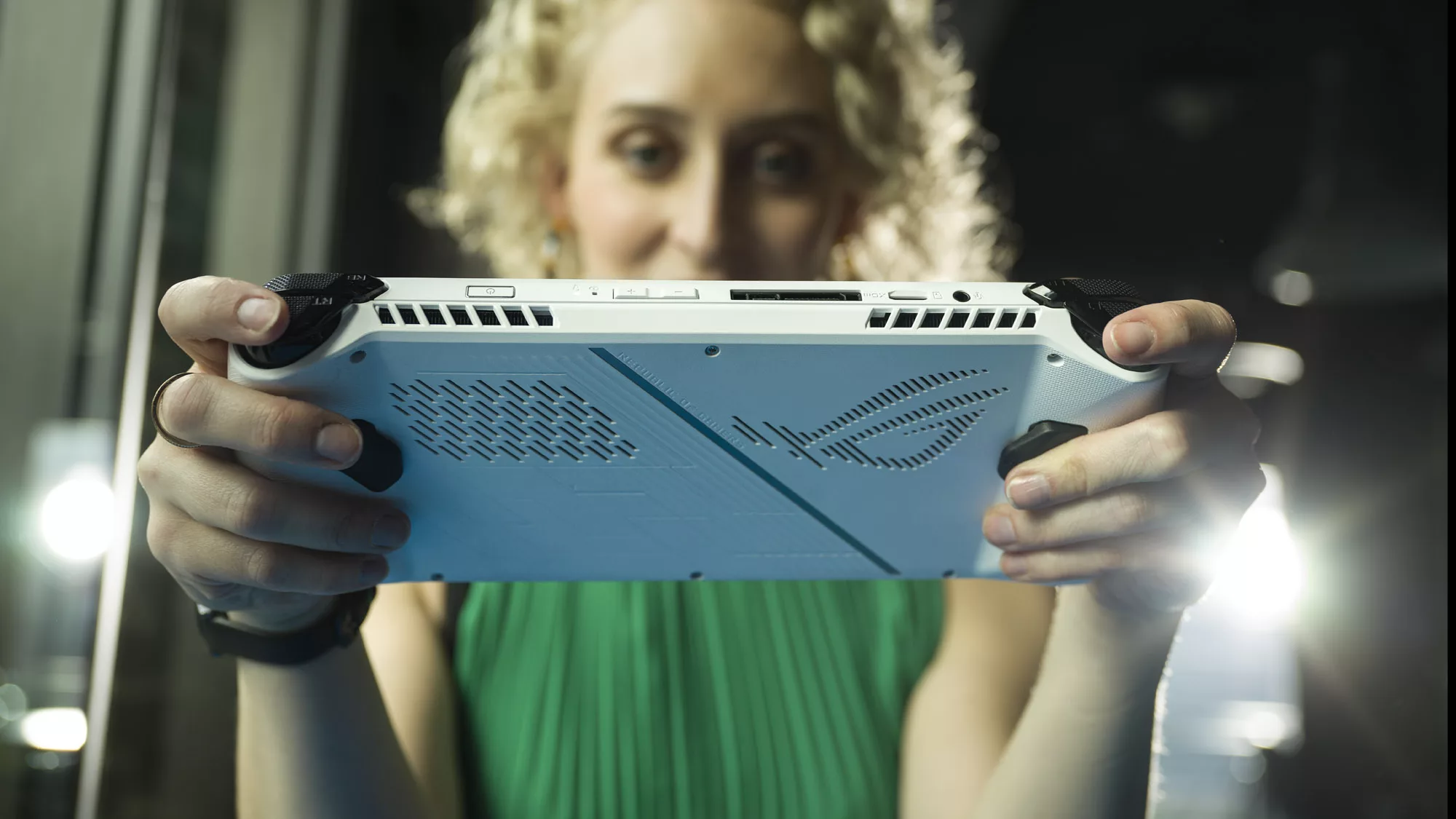A woman holding the ROG Ally in her hands, showing a rear view of the console.