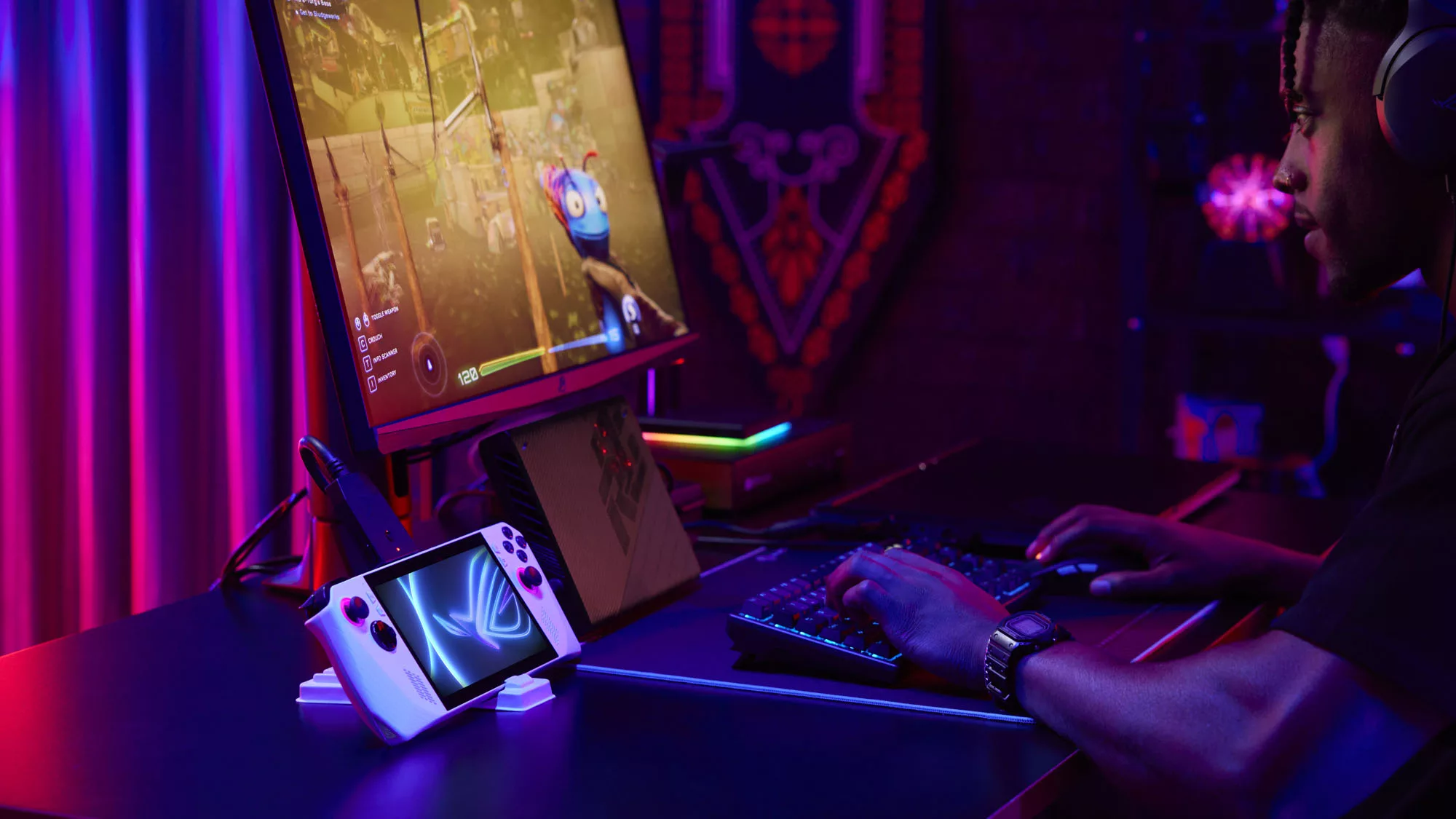 A screenshot of a man in a dark room playing video games with a monitor, mouse, and keyboard hooked up to the ROG Ally and XG Mobile external GPU.