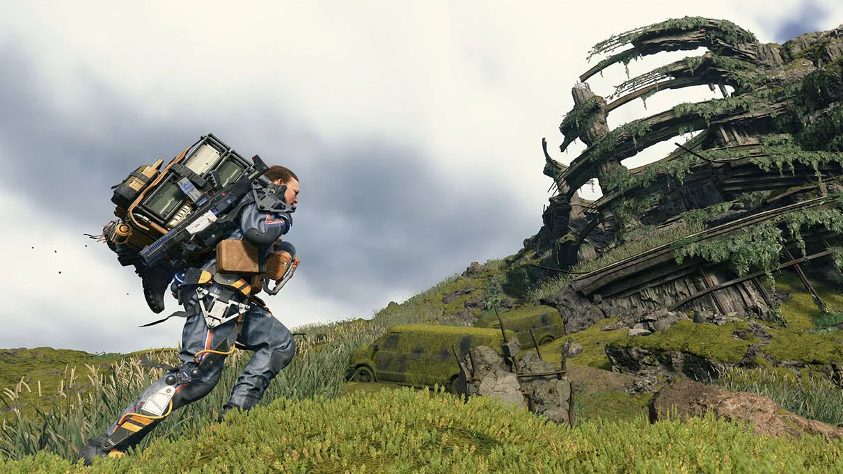 A video game screenshot of a man carrying a large backpack of crates, walking toward an abandoned ruin.