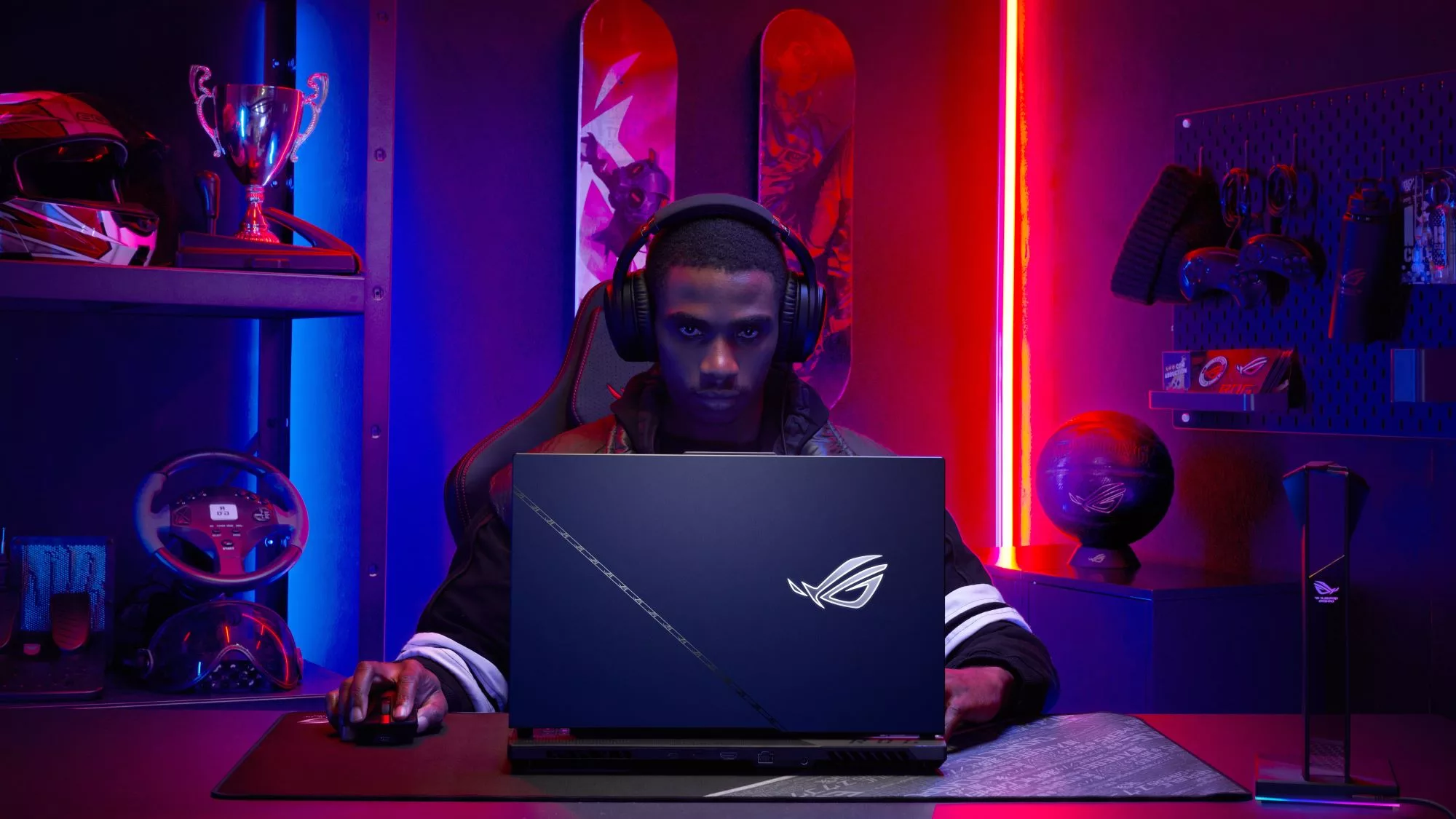 A man looking at the ROG Strix SCAR 17 laptop in a dark room, with the ROG logo visible on the laptop's lid.