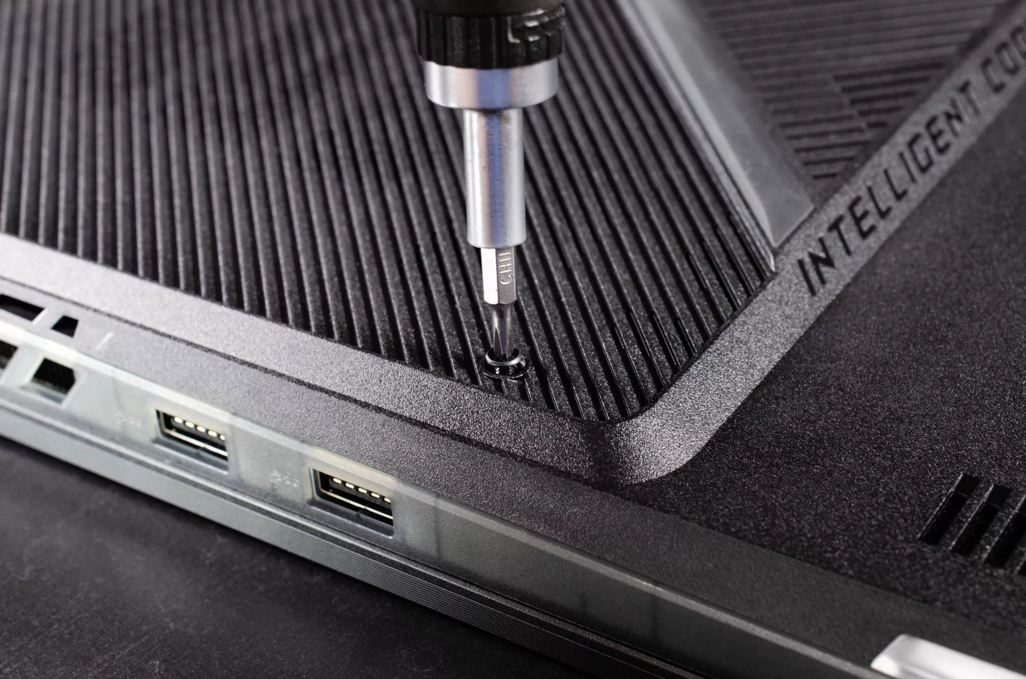 A closeup view of a screwdriver loosening the captive screw that holds the bottom panel of the ROG Strix SCAR 18 in place