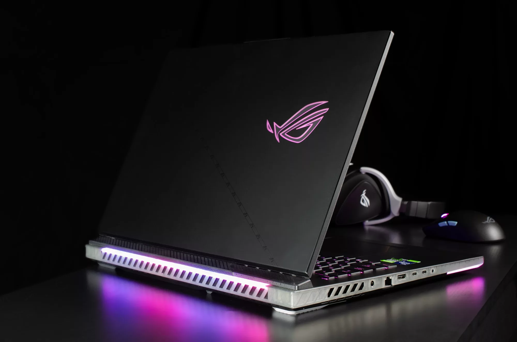 A back view of the ROG Strix SCAR 18 laptop, with an ROG gaming mouse and headset in the background